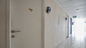 A corridor with a closed door, a sign with a number, and a security camera. - Room Rendi @ Apt Dramaga Tower (Dramaga)
