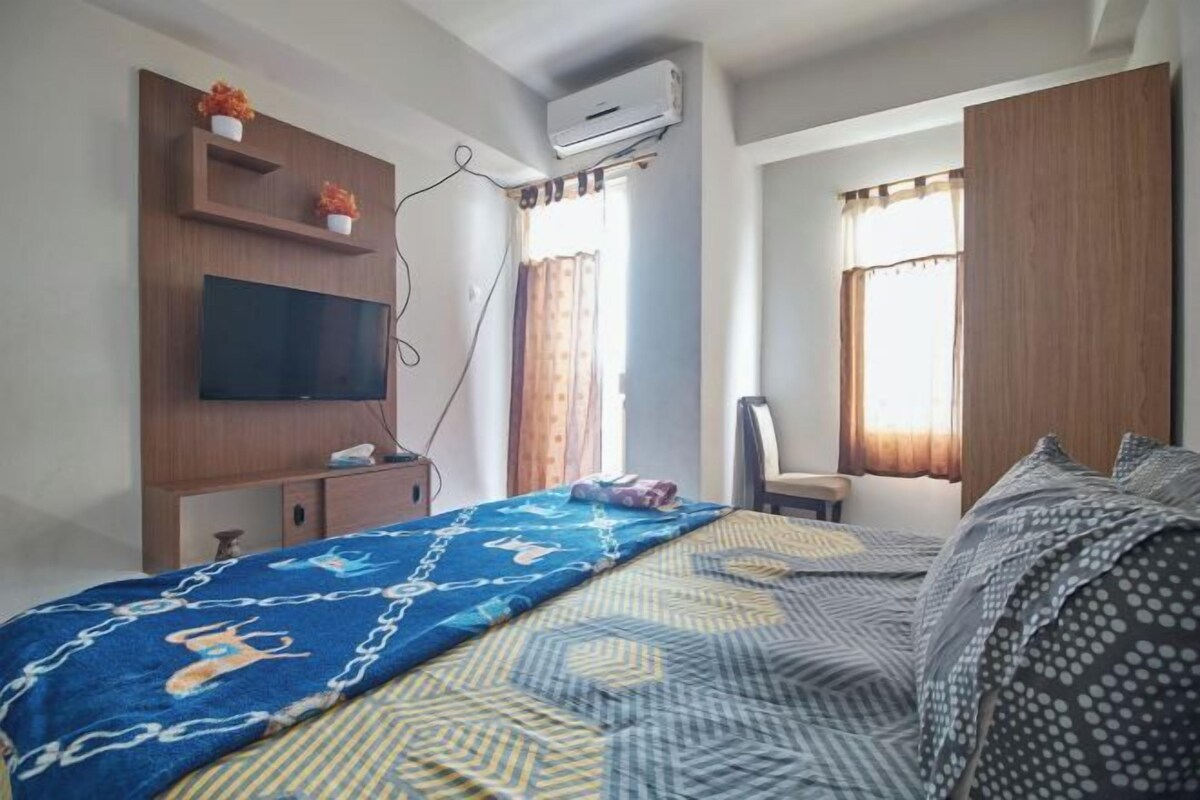 Una habitación de hotel con cama, televisión, escritorio y silla.