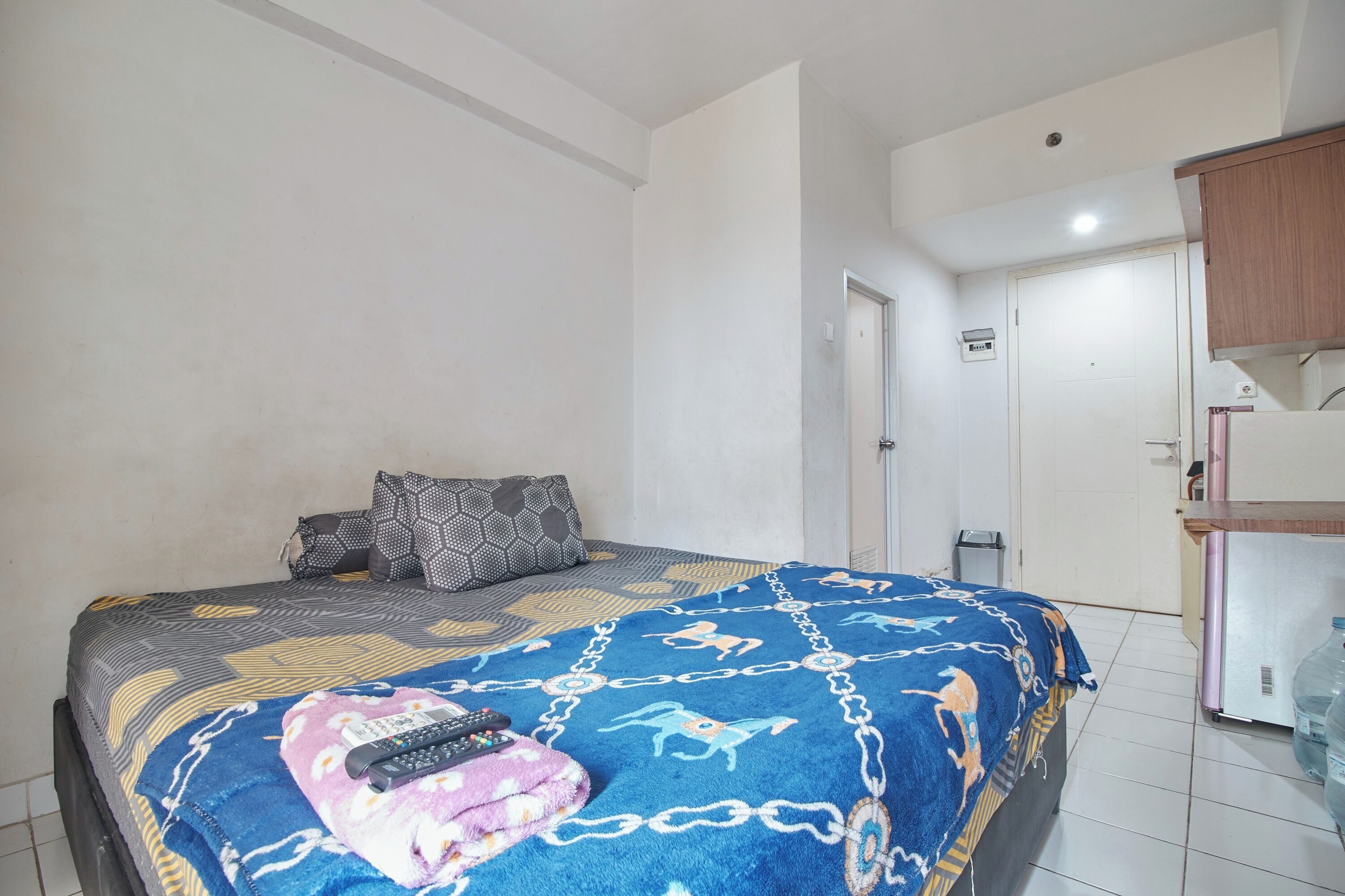 Ein Schlafzimmer mit Bett, Kissen, Decke und Fernbedienung.
