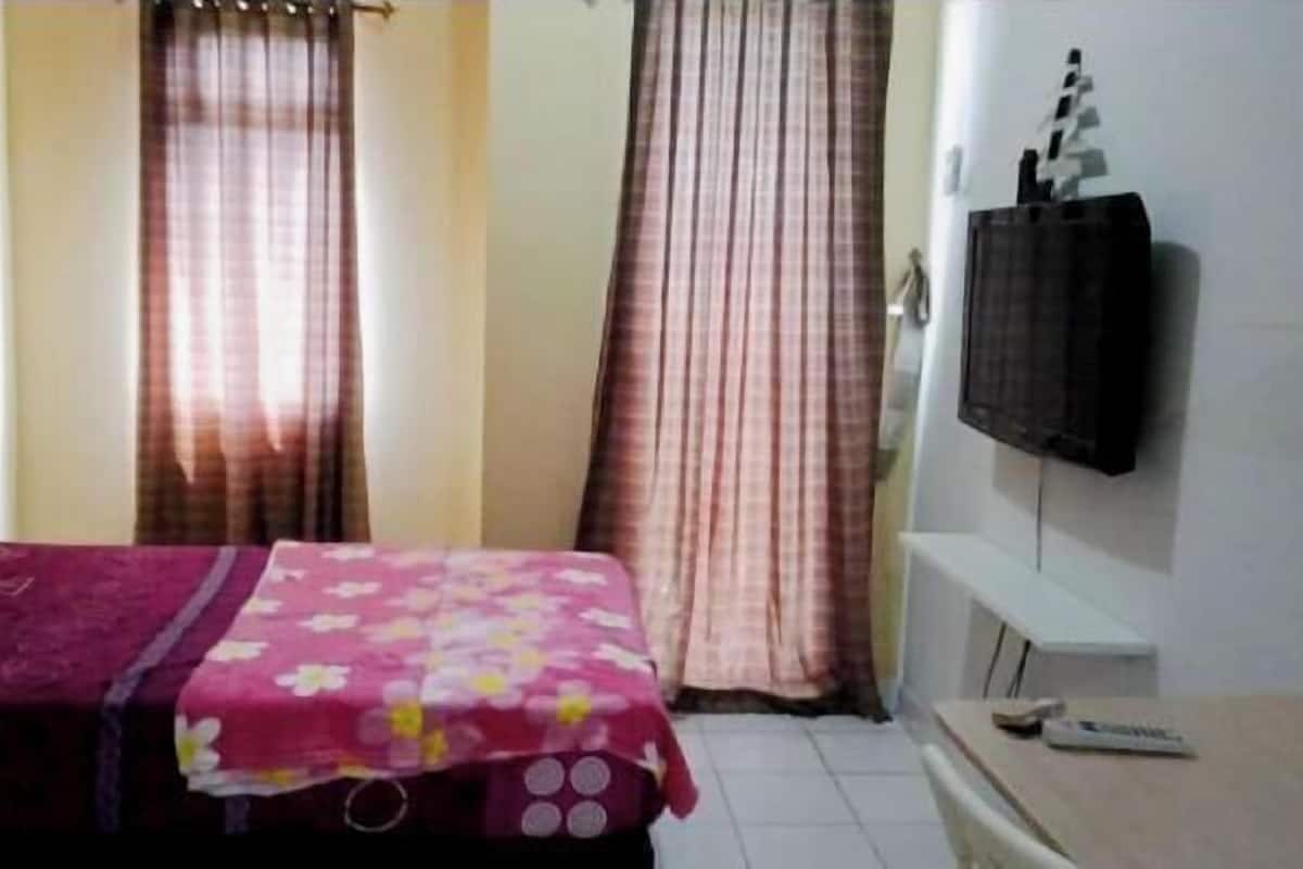 A room with a bed, curtains, a TV, and a small table.