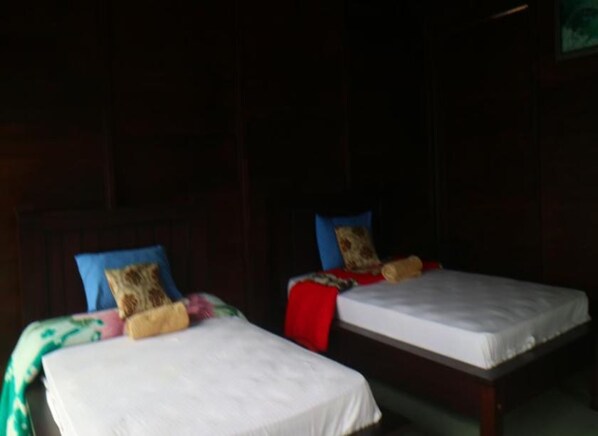 Dos camas individuales con cabeceras, cada una con una almohada y una manta.