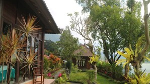 A garden with a pathway leading to a building with a tiled roof. - Batur Green Lakeview in Kintamani Bali (Kintamani)
