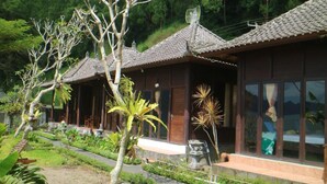 A row of traditional wooden buildings with tiled roofs, surrounded by lush greenery and a pathway. - Batur Green Lakeview in Kintamani Bali (Kintamani)