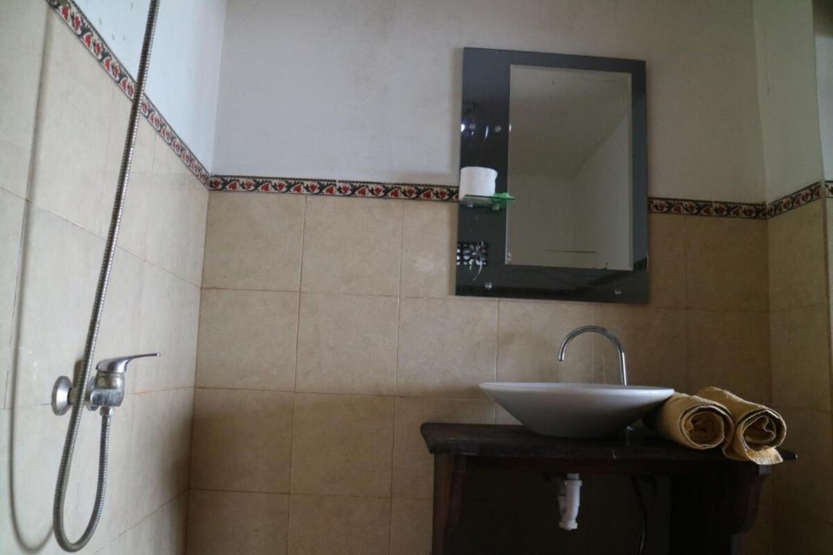 A bathroom with a sink, mirror, and shower.