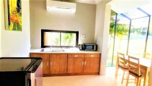 Una cocina con armarios de madera, un microondas y una ventana.