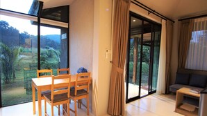 Una sala de estar moderna con comedor, grandes puertas correderas de vidrio hacia un jardín y un sofá.
