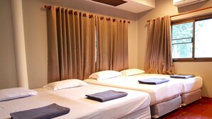 Habitación de hotel con dos camas, cortinas color beige, una ventana con vistas y un equipo de aire acondicionado.