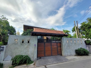 A modern house with a gated entrance, a covered porch, and a large window.