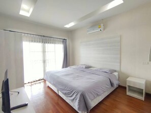 A bedroom with a bed, a nightstand, a TV, and an air conditioning unit.