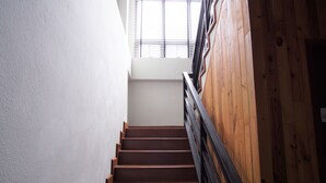 A staircase with wooden steps and black railings, leading to a landing with a window. - Lan House Pool Villa (Chiang Mai)