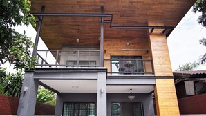 A two-story building with a balcony, a covered patio area, and a motorcycle parked outside. - Lan House Pool Villa (Chiang Mai)