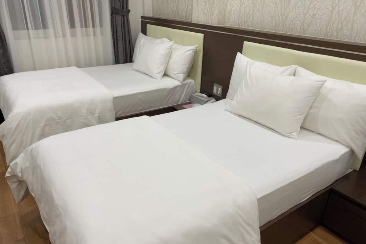 Two adjacent beds with white bedding, a wooden headboard, a telephone, and a nightstand.