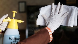 A person cleaning a window with a spray bottle and a cloth.