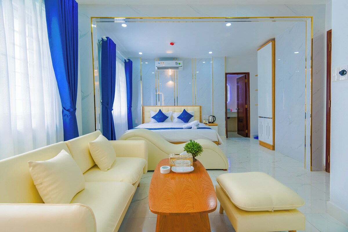 Ein Hotelzimmer mit Bett, Sofa, Couchtisch und einem durchgehenden Türrahmen einsehbarer Badezimmer.