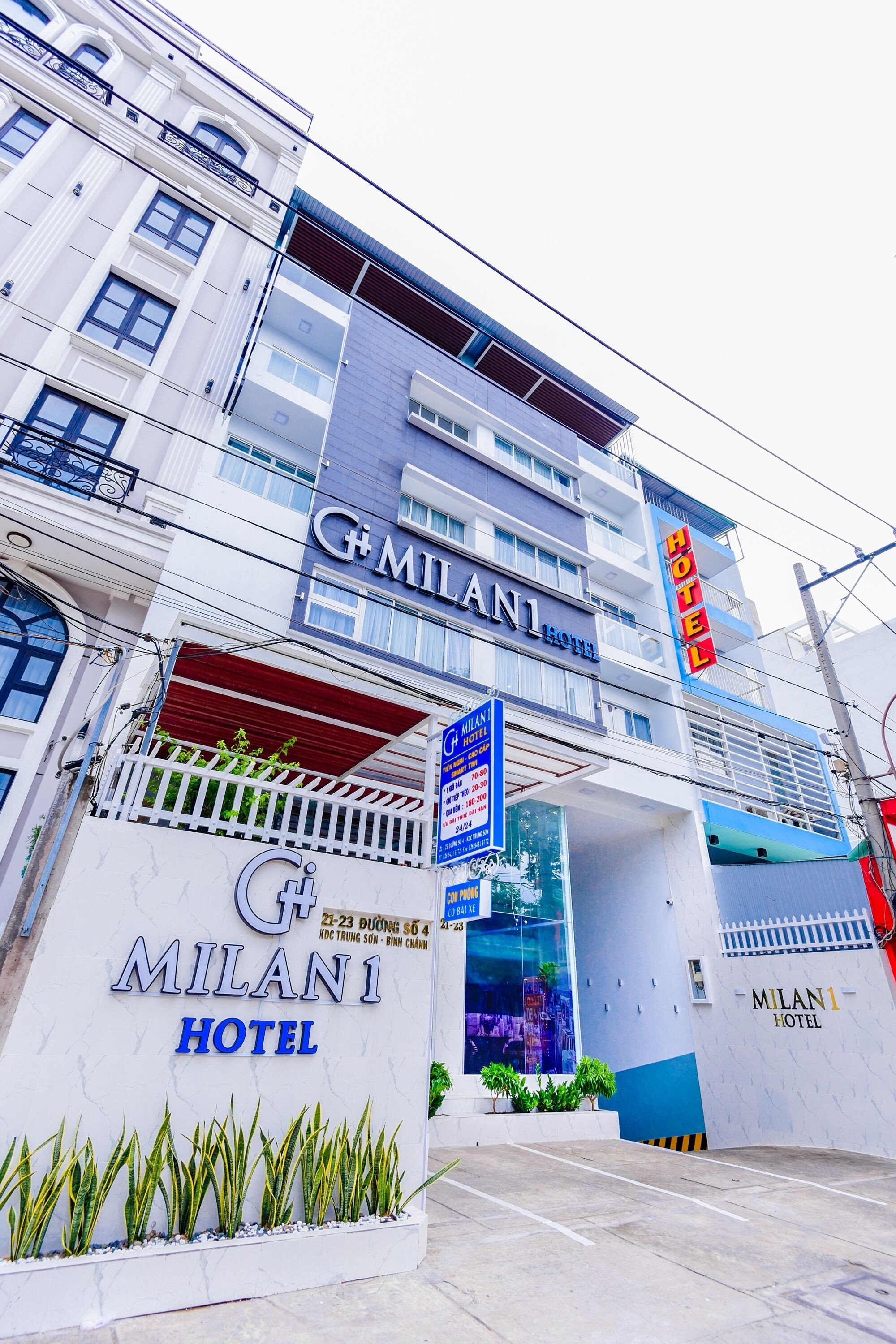 The exterior of the MILANI HOTEL with a prominent sign, a gated entrance, and a view of the surrounding area.
