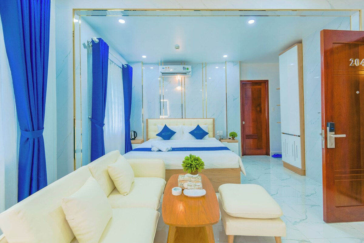 Une chambre d’hôtel avec un lit, un canapé, une table basse et une porte portant un numéro.