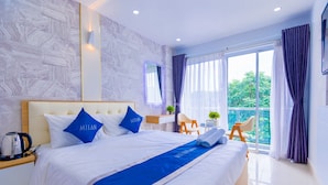 Une chambre d’hôtel avec un grand lit, une table de chevet, un bureau et un balcon avec des rideaux.