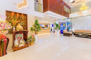 Um hall de hotel moderno com balc ão de recepção, área de estar e elementos decorativos como estátuas e flores.