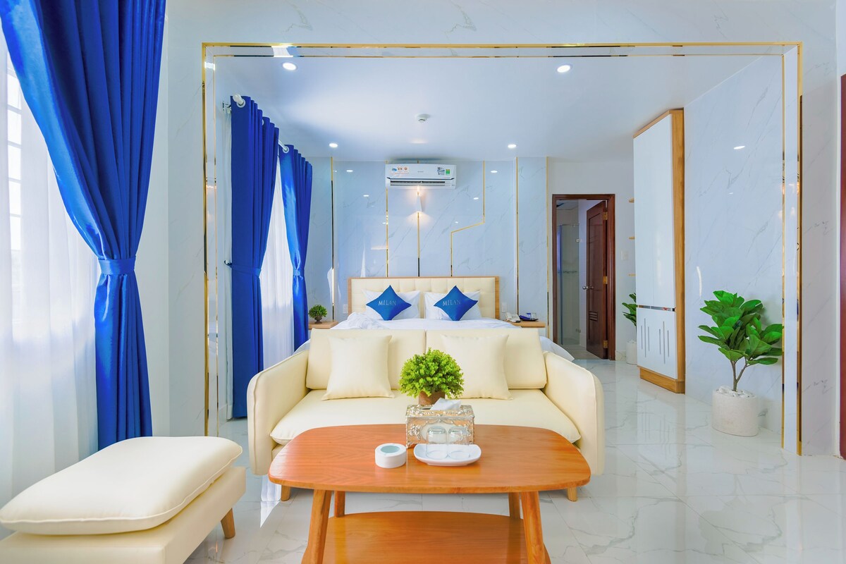 Une chambre d’hôtel moderne, équipée d’un lit, d’un canapé, d’une table basse et d’une plante en pot.