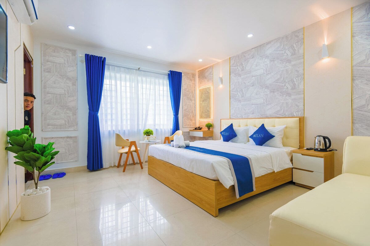 Une chambre d’hôtel moderne, dotée d’un grand lit, de tables de chevet, d’un bureau et d’une chaise.