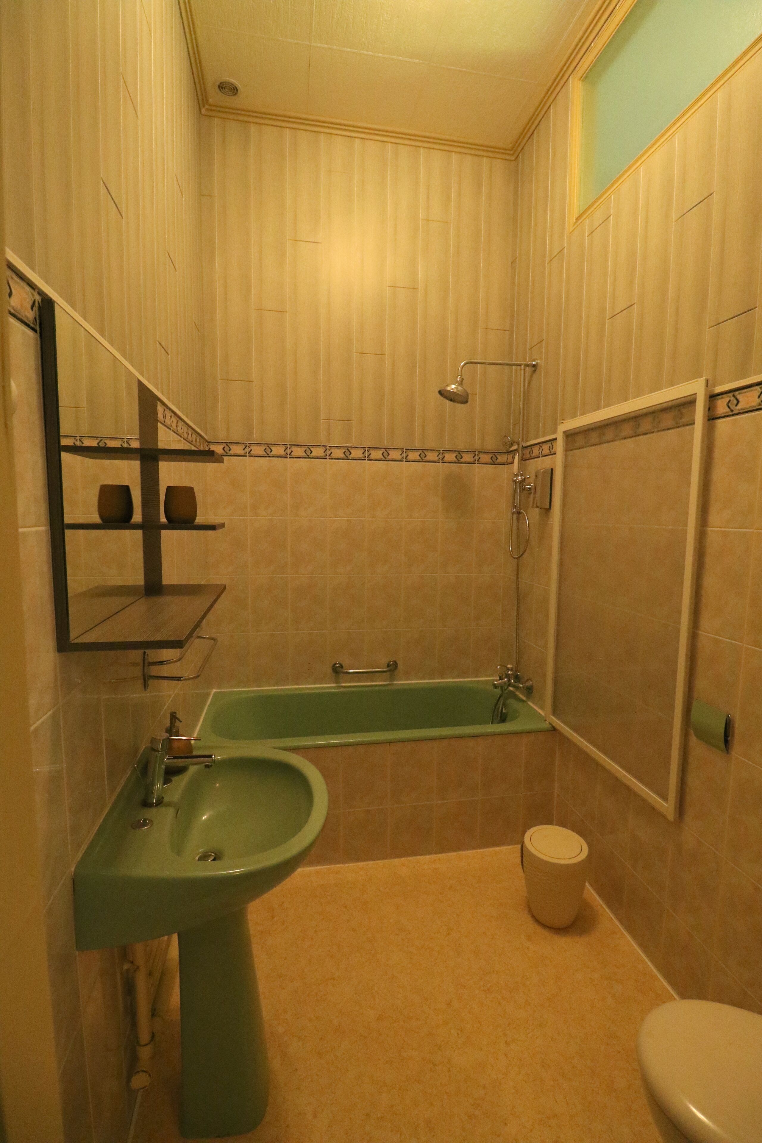A bathroom with a green sink, a bathtub, a toilet, and a shower.