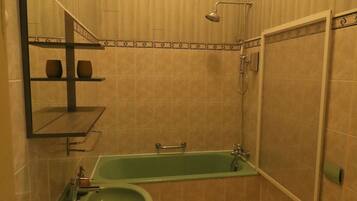 A bathroom with a green sink, a bathtub, a toilet, and a shower.