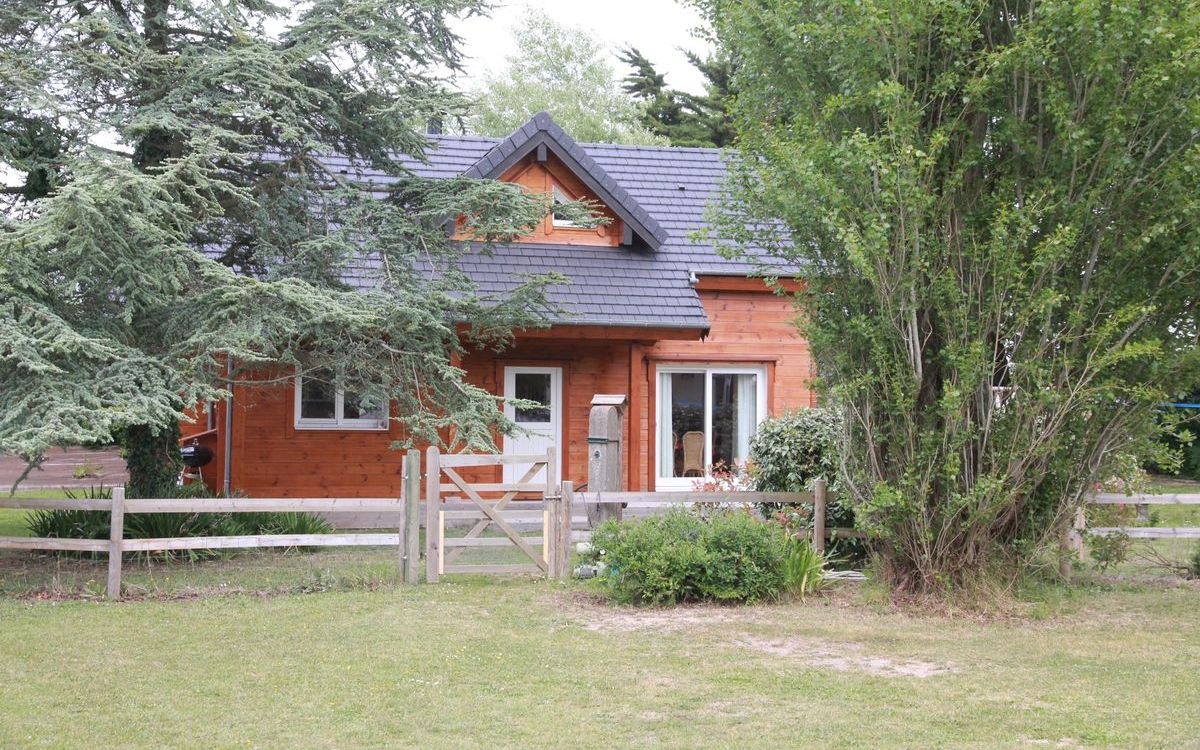 Une cabane en bois avec un toit en pente, une porte d’entrée et une petite fenêtre.