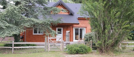 Une cabane en bois avec un toit en pente, une porte d’entrée et une petite fenêtre.