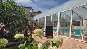 Un invernadero con techo de cristal, una piscina y zona de estar exterior.