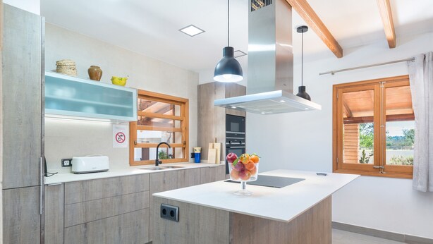 A modern kitchen with wooden cabinets, a central island, and a built-in oven. - YESERO. Beautiful villa near Pollensa (Pollensa)