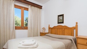 A bedroom with a wooden bed, a nightstand, a lamp, and a window with curtains. - YESERO. Beautiful villa near Pollensa (Pollensa)