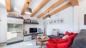 A modern living room with a grey sofa, red cushions, a wooden coffee table, and a flat-screen TV. - YESERO. Beautiful villa near Pollensa (Pollensa)