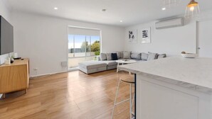 A modern kitchen with a white countertop, a wooden dining table, and a bar stool.