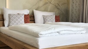 A wooden bed with white bedding and patterned pillows.