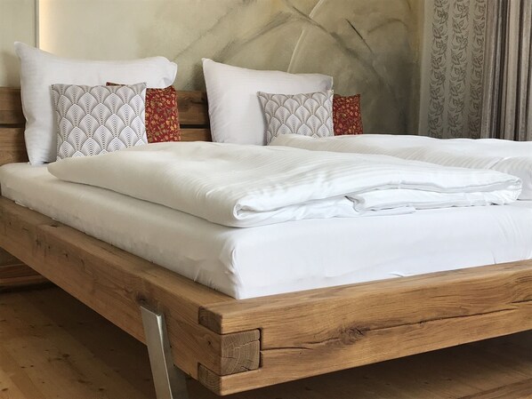 A wooden bed with white bedding and patterned pillows.