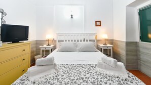 A neatly arranged hotel room with a bed, bedside lamps, a television, and a small table. - Casa Da Aldeia (Alcaria Ruiva Mértola Beja)