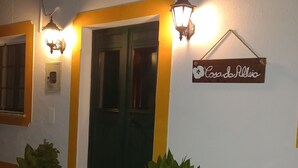 A building entrance with a green door, two potted plants, and a sign reading "Casa de Albergue". - Casa Da Aldeia (Alcaria Ruiva Mértola Beja)