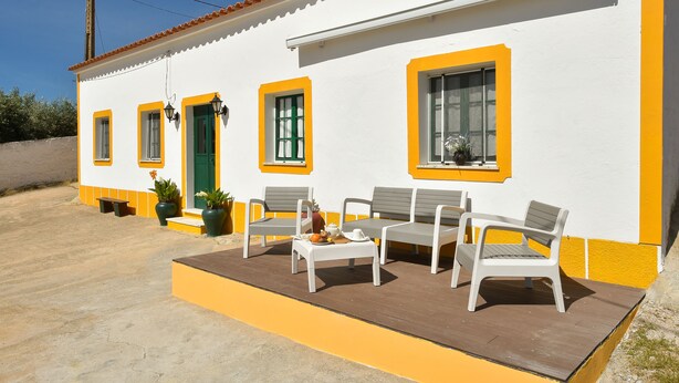 A white building with yellow trim and a patio area with outdoor furniture. - Casa Da Aldeia (Alcaria Ruiva Mértola Beja)