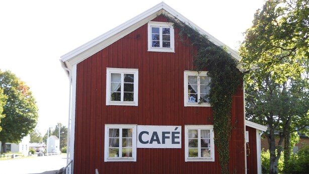Um edifício vermelho com uma placa que diz 'CAFÉ'.