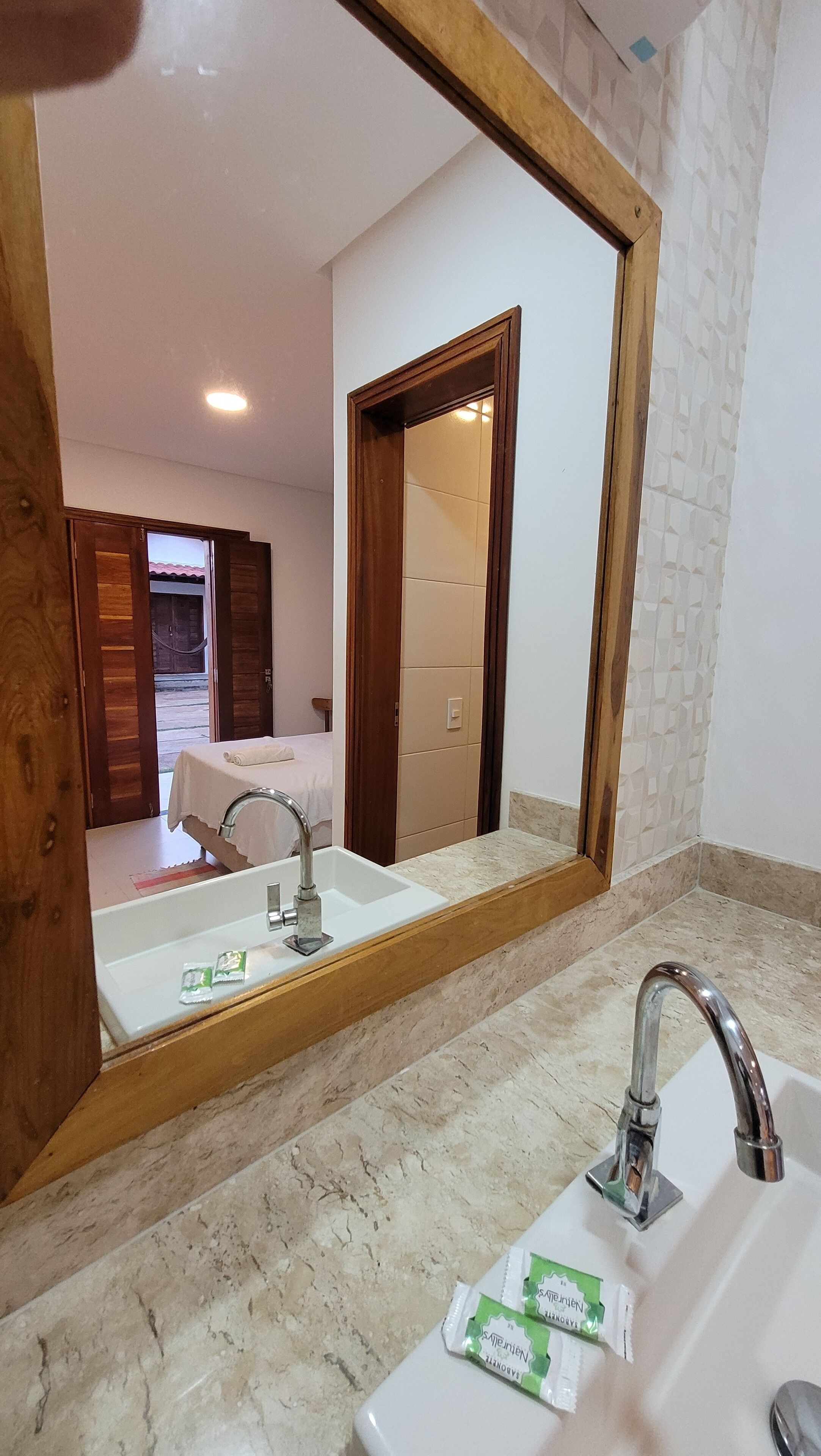 Un baño con un espejo grande, un lavamanos con grifo y una encimera.