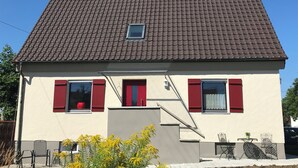 A two-story house with a brown tiled roof, red shutters, and a small window. - Holiday home with sauna and garden lounge (Lauingen)