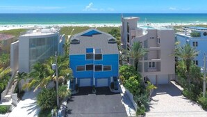 Un hôtel de bord de mer au design moderne, avec un bâtiment bleu imposant, une piscine et une vue sur l’océan.