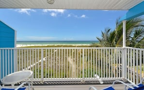 A balcony with a view of a beach and palm trees.