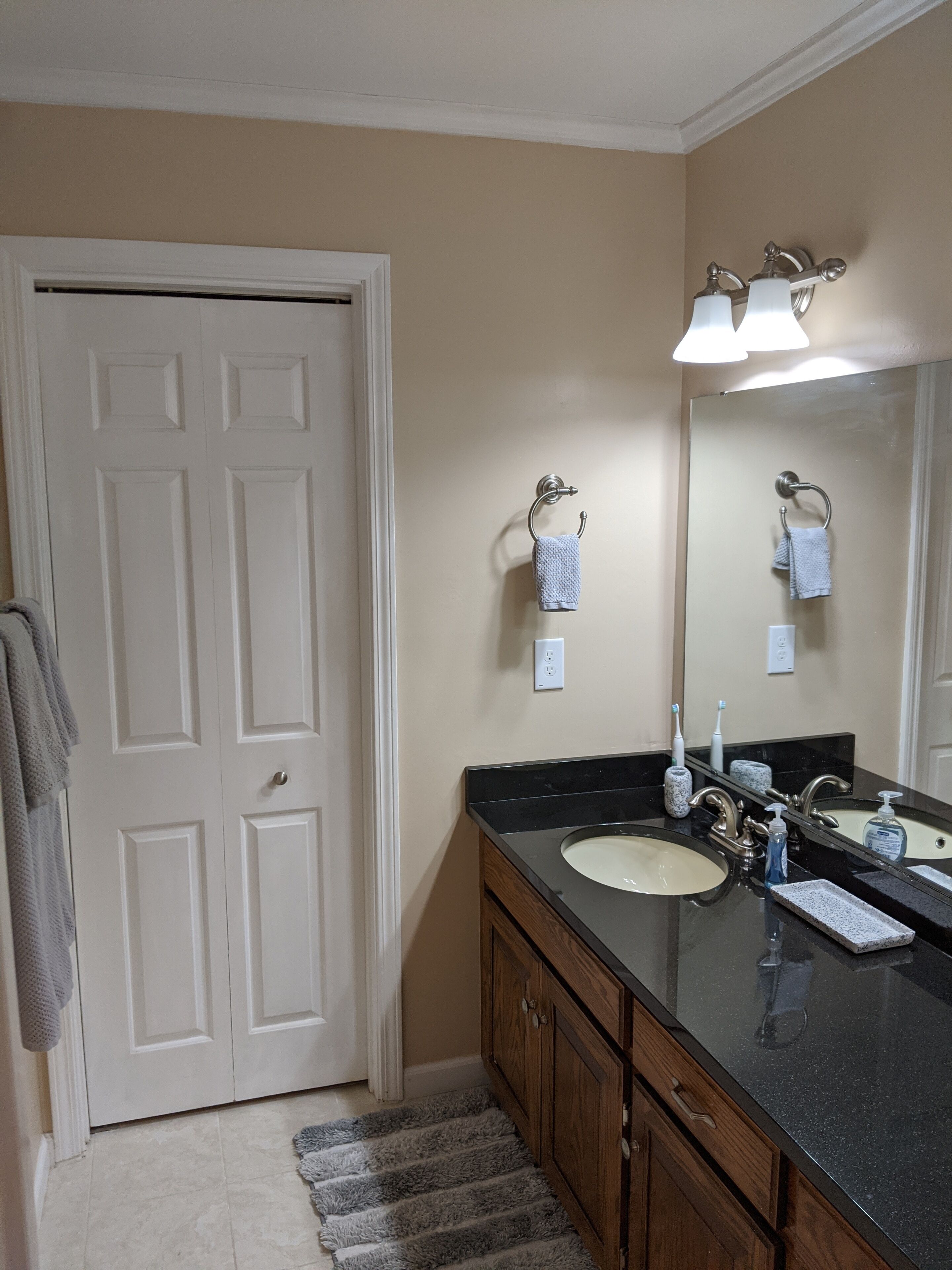 Une salle de bain avec deux lavabos, un miroir et une porte.