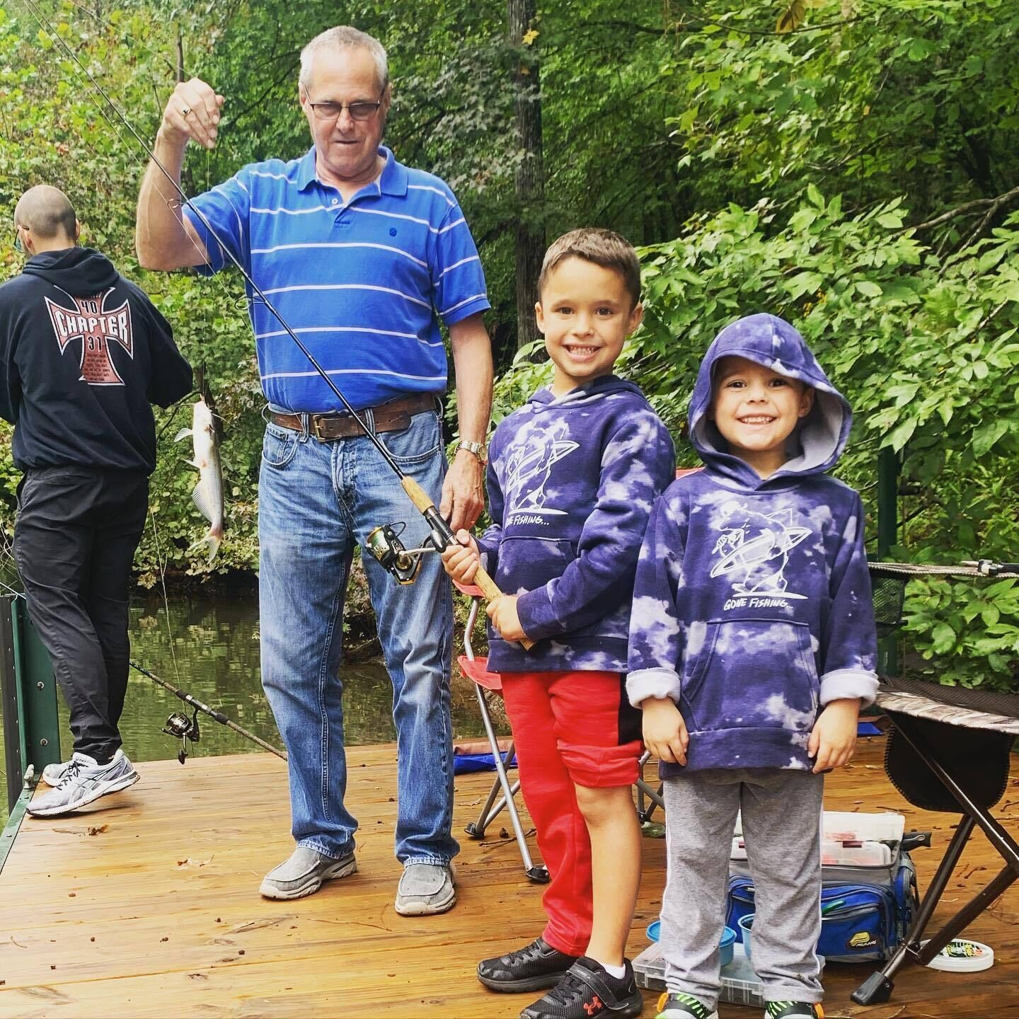 A wooden deck with fishing rods and a fish, surrounded by greenery.