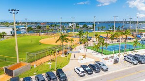 Un campo de béisbol con un estacionamiento y vista al océano.