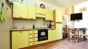 A kitchen with yellow cabinets, a built-in oven, and a stone fireplace.