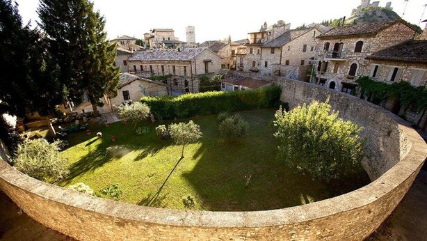 A courtyard with a circular stone wall, surrounded by stone buildings with traditional architecture.