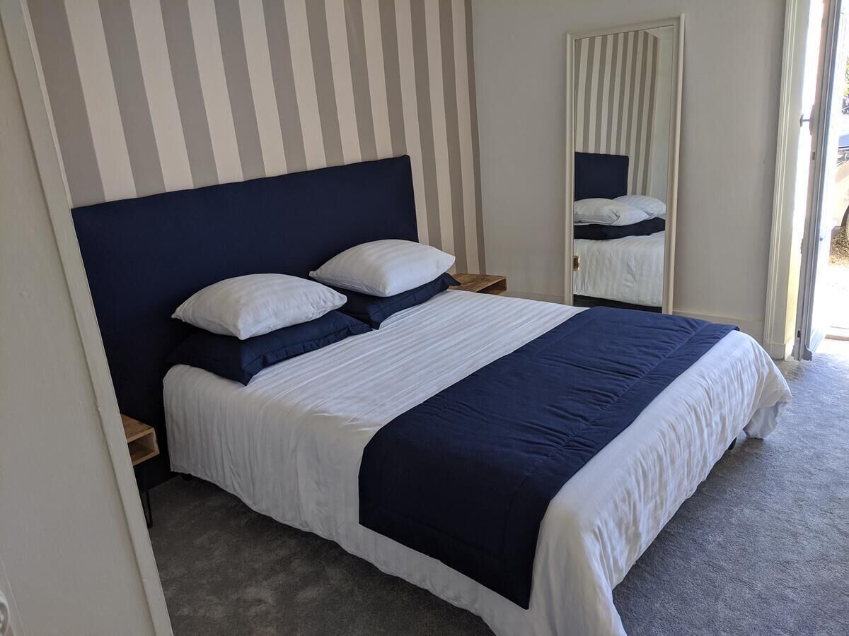Une chambre à coucher avec un grand lit, un papier peint à rayures et un miroir.