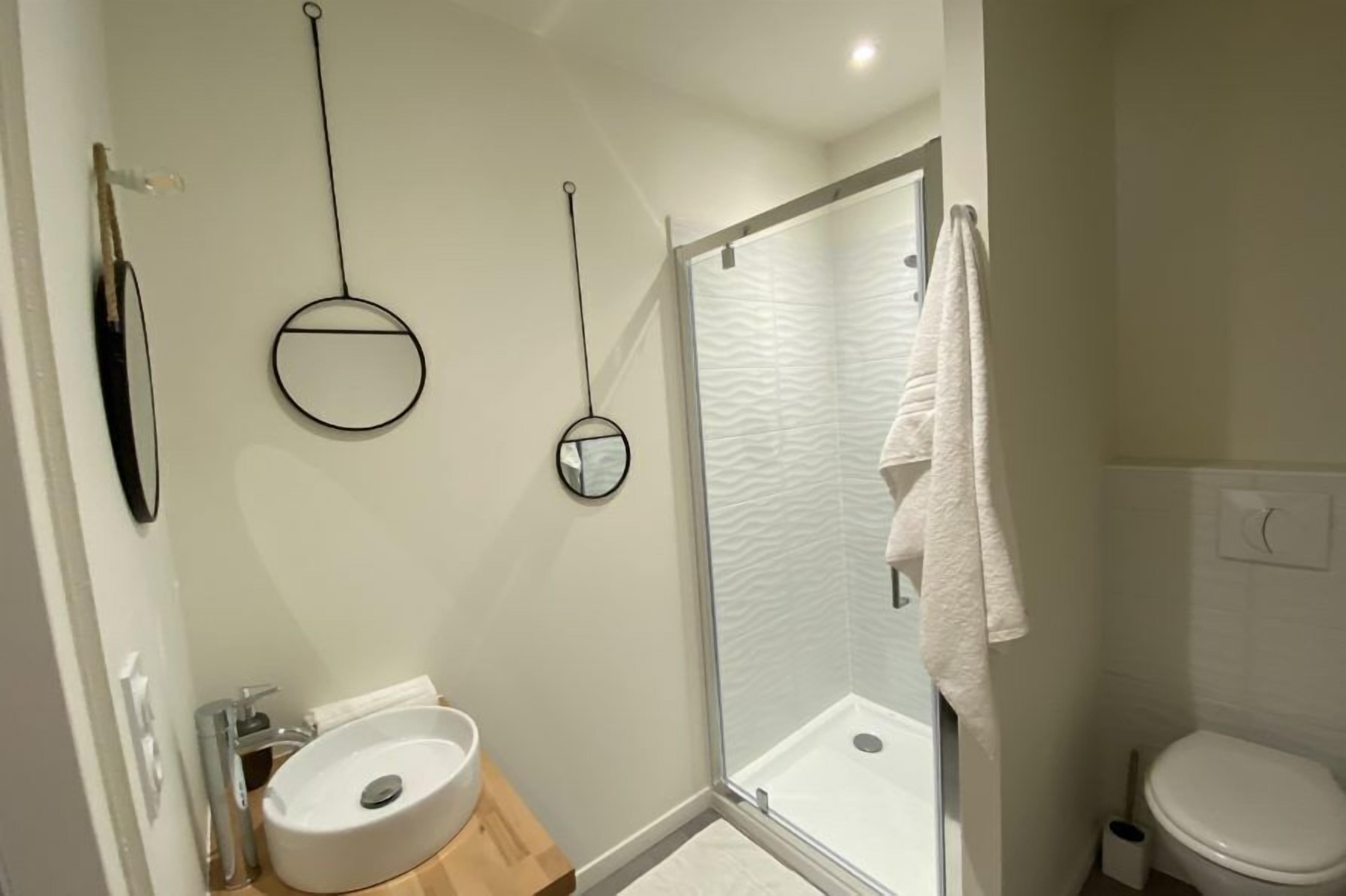 Un baño con lavamanos blanco, cabina de ducha de cristal y retrete.